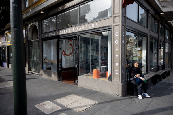 Woman sitting outside of Ritual Coffee Roasters Haight street cafe