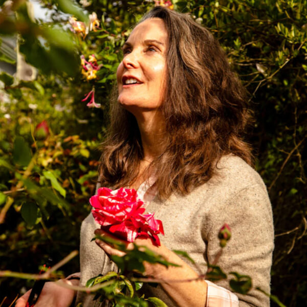 Joanne looking up into the trees holding a red flower