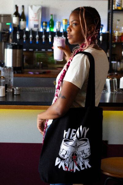 Person wearing black tote bag that says "heavy drinker"